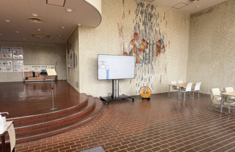 水道局庁舎1階のエントランスホールの中央付近にモニターがあり、その右下に消火栓用鉄蓋が設置されている。