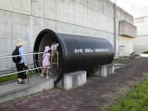 直径2メートルの水道水を送るための送水管の模型の中をくぐる参加者の様子